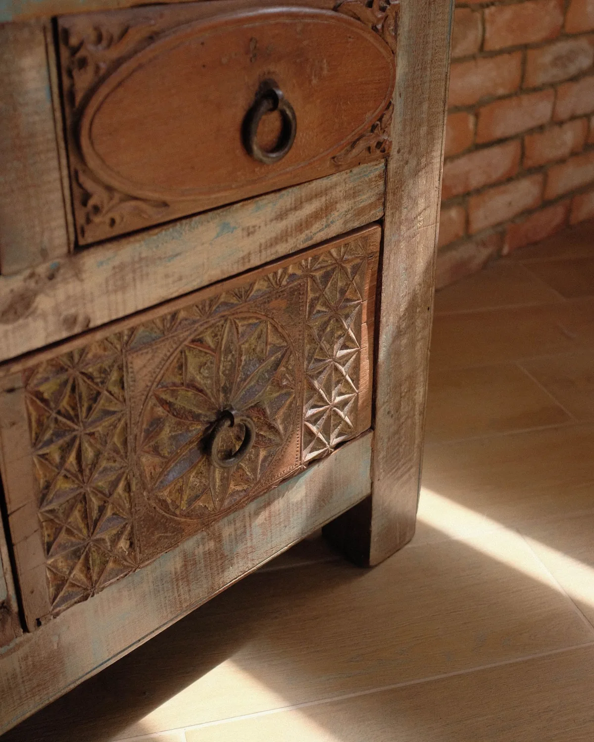 Carved wooden drawers with metal ring handles, photographed in natural light.