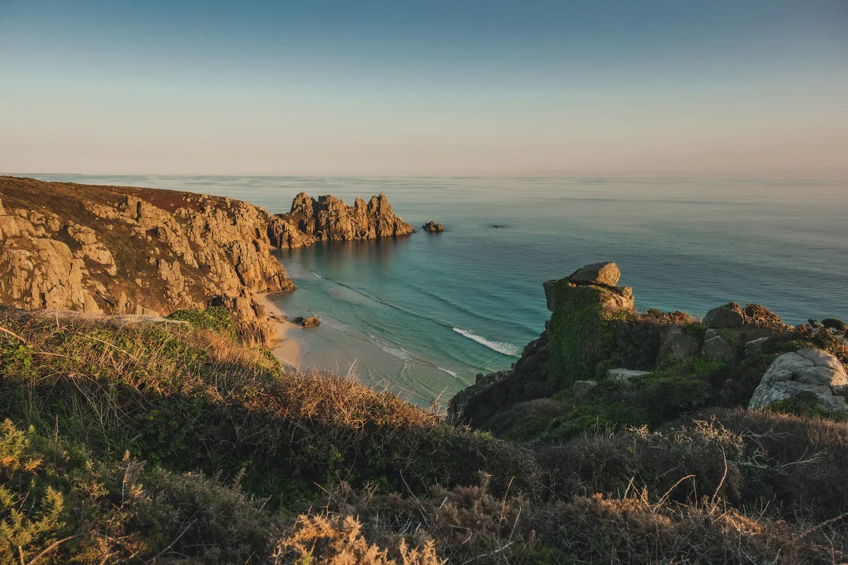 Golden evening light on a rocky cove and the sea on the Cornwall coast.