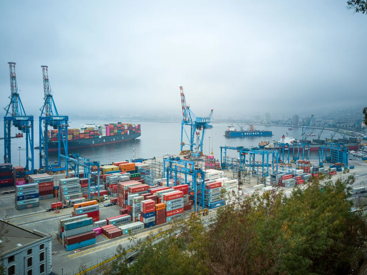 Container ships, quayside cranes and stacked shipping containers at Valparaíso port.