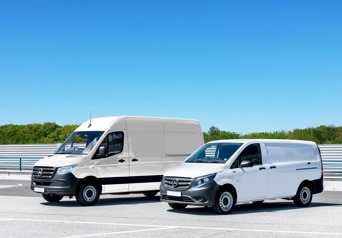 Two white panel vans of different sizes parked on a paved area.